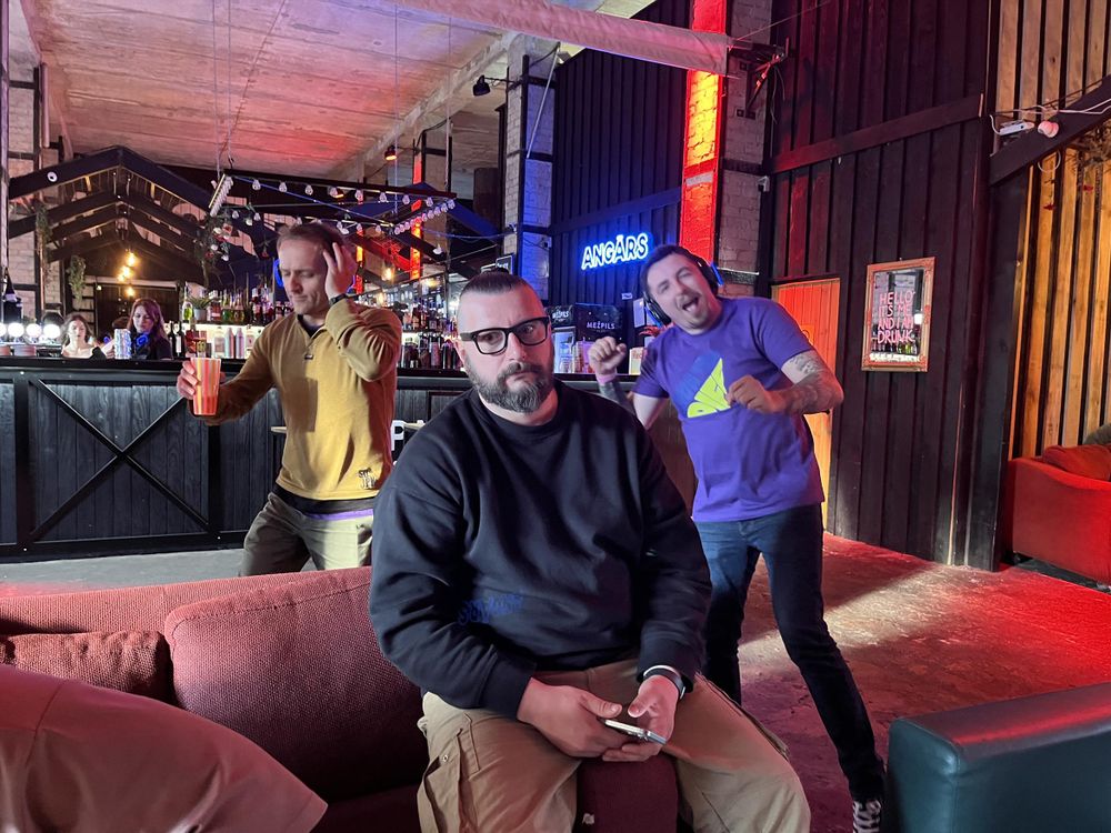 A sad guy without headphones and two guys having fun in headphones. 
