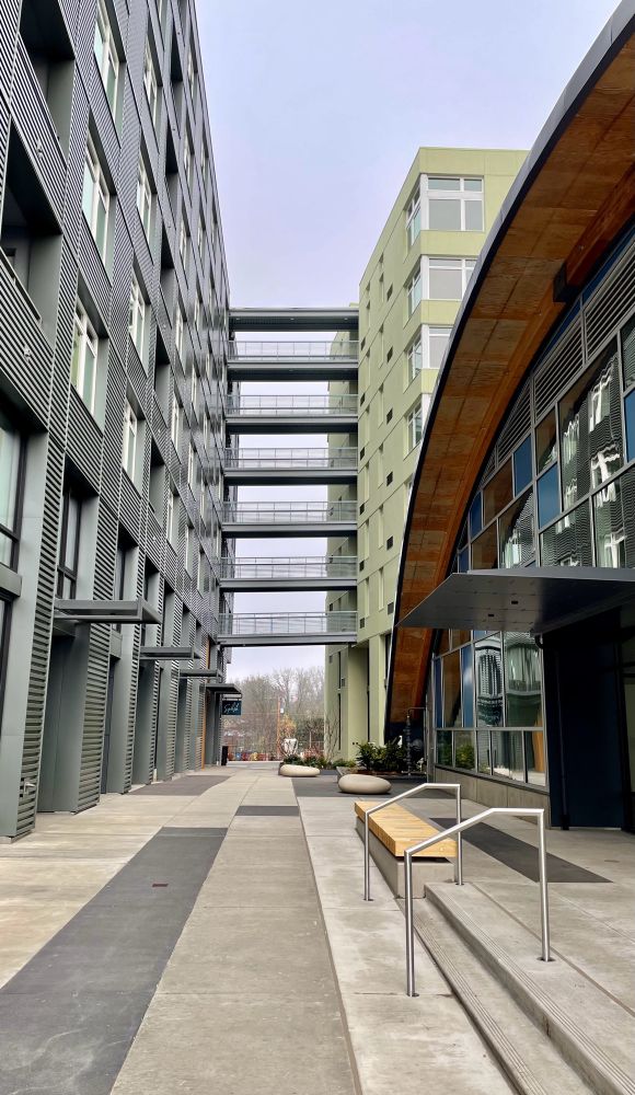 Two new apartments buildings with open walkways connecting them on floors two through eight. 