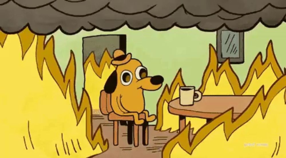 a cartoon dog is sitting at a table with a cup of coffee surrounded by fire .