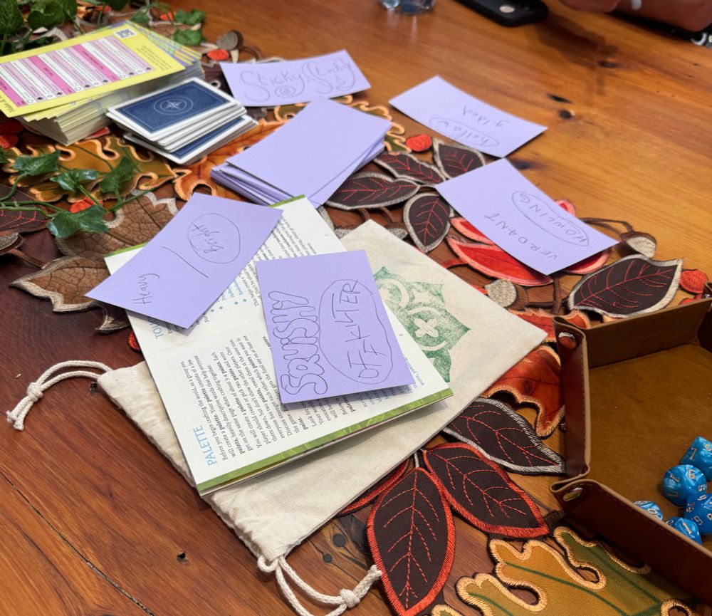 An autumnal spread on the table with notecards that are answering prompt from the TTRPG a land once magic