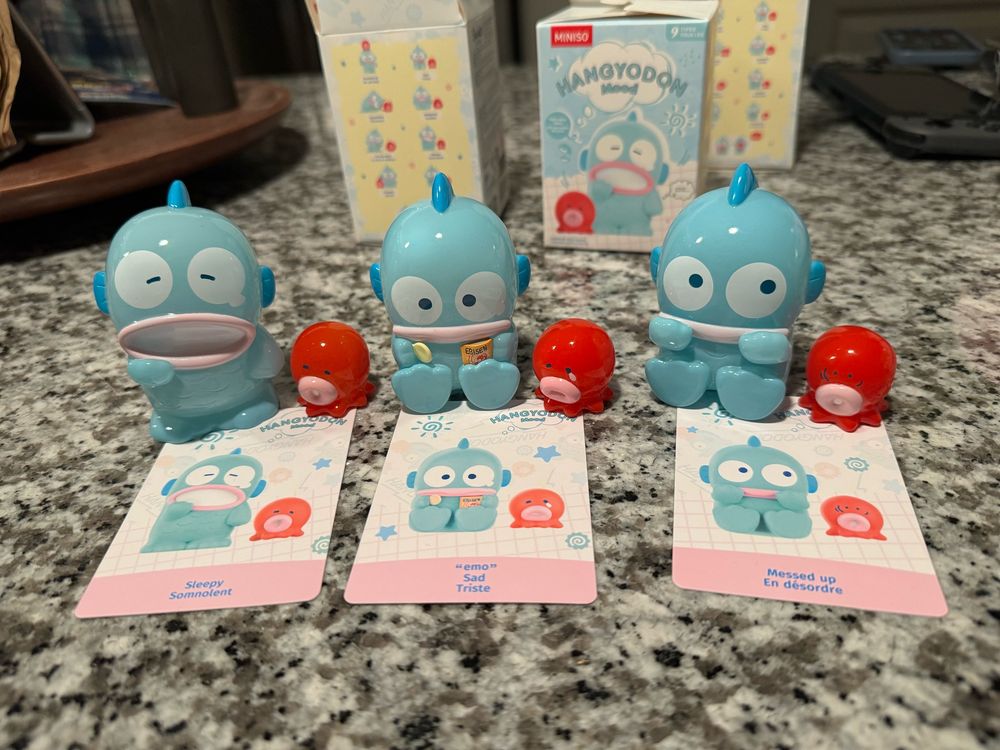 Hangyodon Sanrio character (blue round kawaii sea monster with a small red octopus friend) 3 blind boxes. Each showing a different collectible in different emotions: sleepy, emo, and messed up