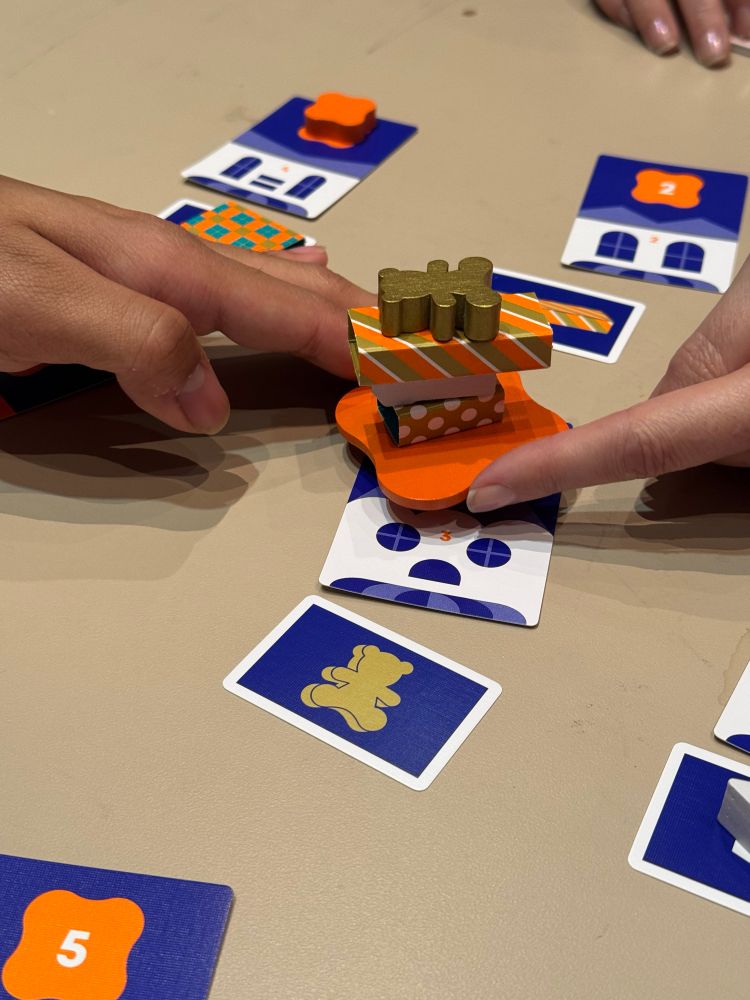 Two hands with only one finger on it holding a small wooden platform with presents stacked upon it 