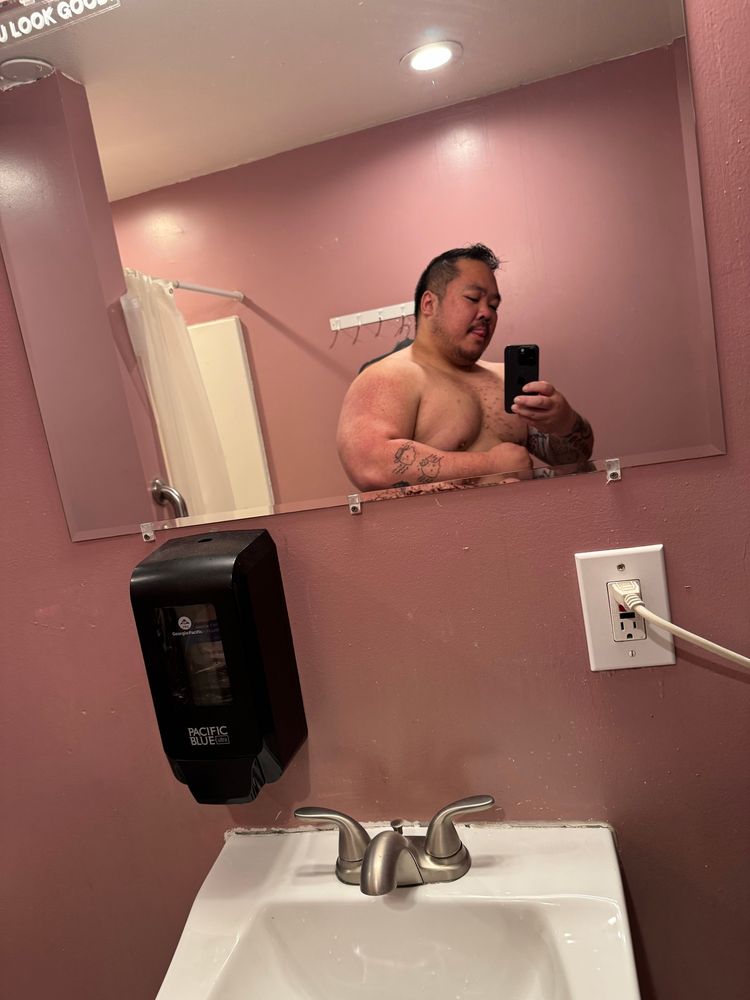 Danny flexing in a mirror with tongue out shirtless