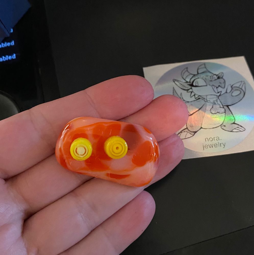 little orange and yellow googly-eyed weird face made of glass, I love him