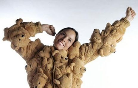 A woman stretching and smiling while wearing a shirt made entirely of teddy bears.