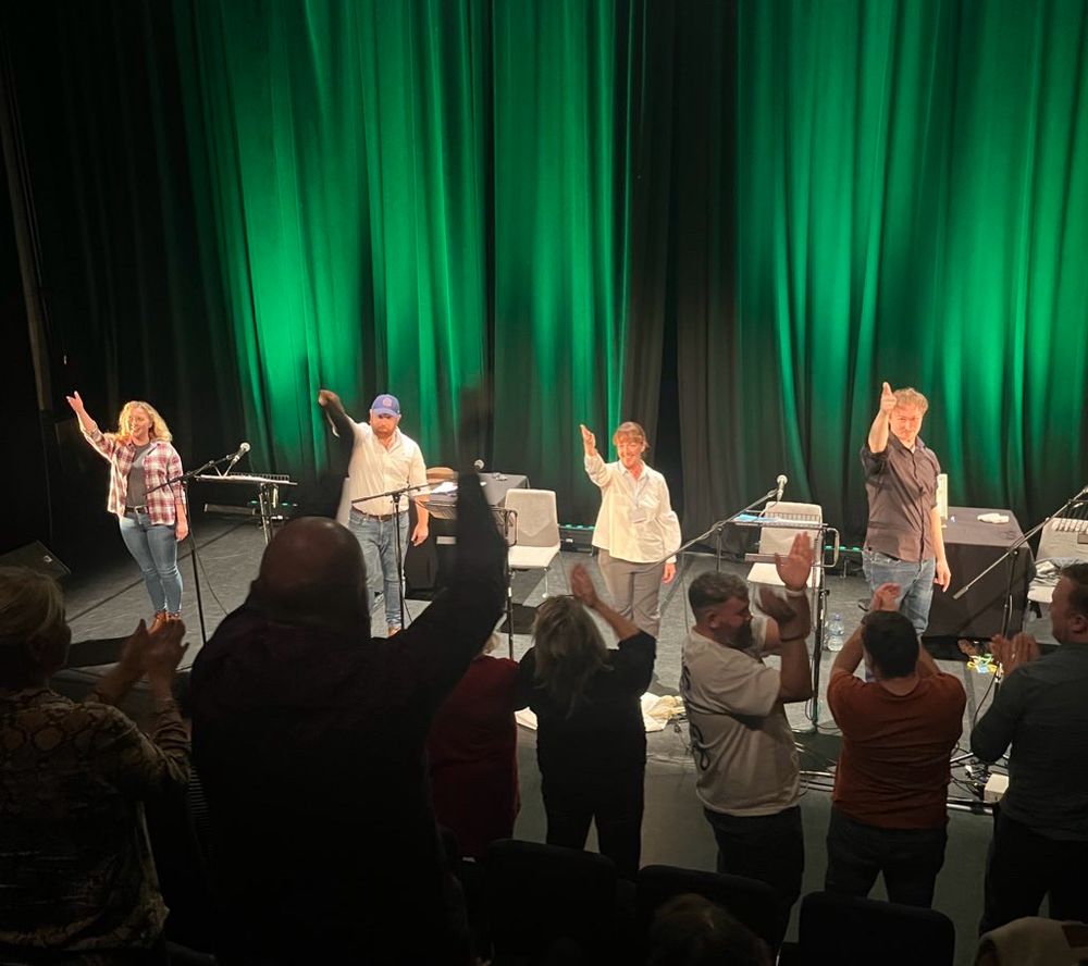 Actors during a curtain call, bowing. Green lights on back curtain. 