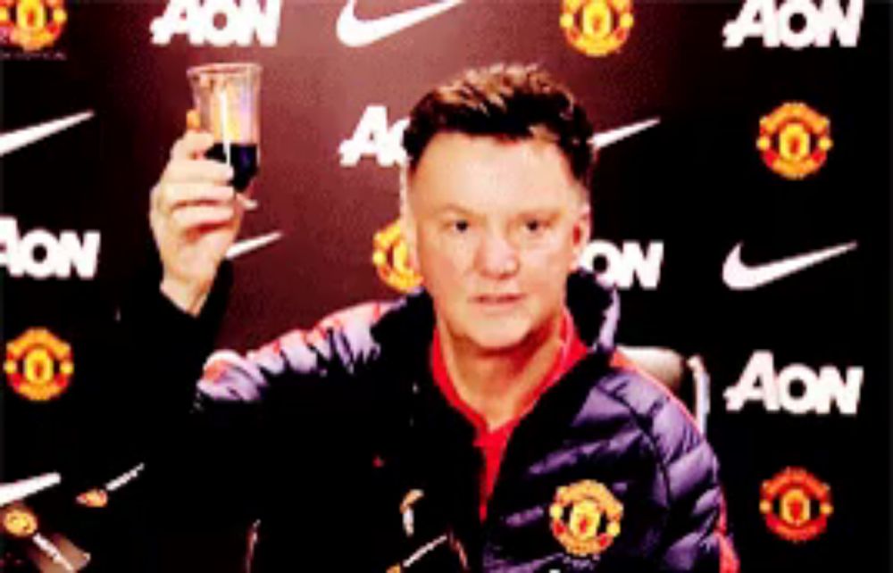 a man in a manchester united jacket holds a glass in front of a nike ad