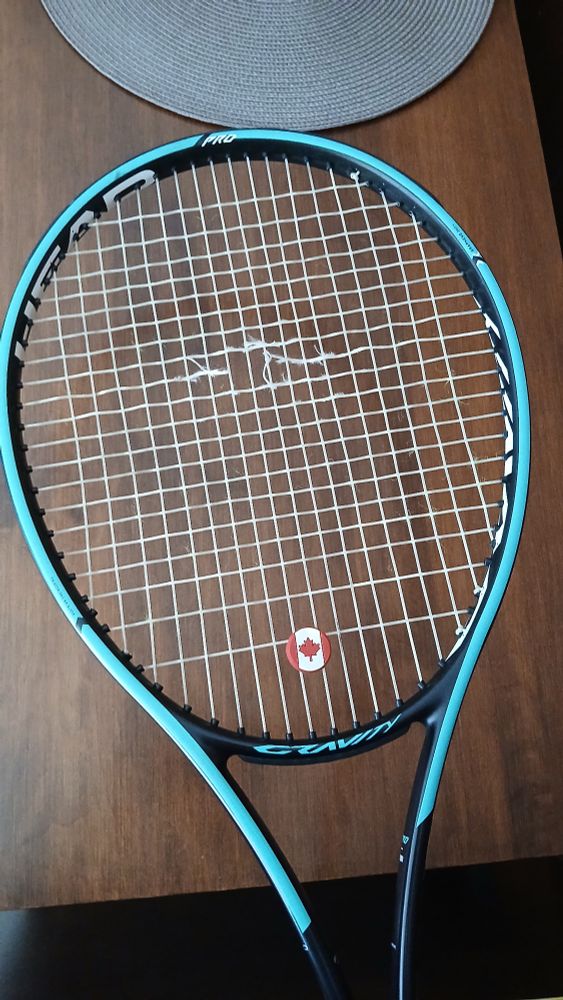 Head Gravity Pro tennis racquet with a broken string.