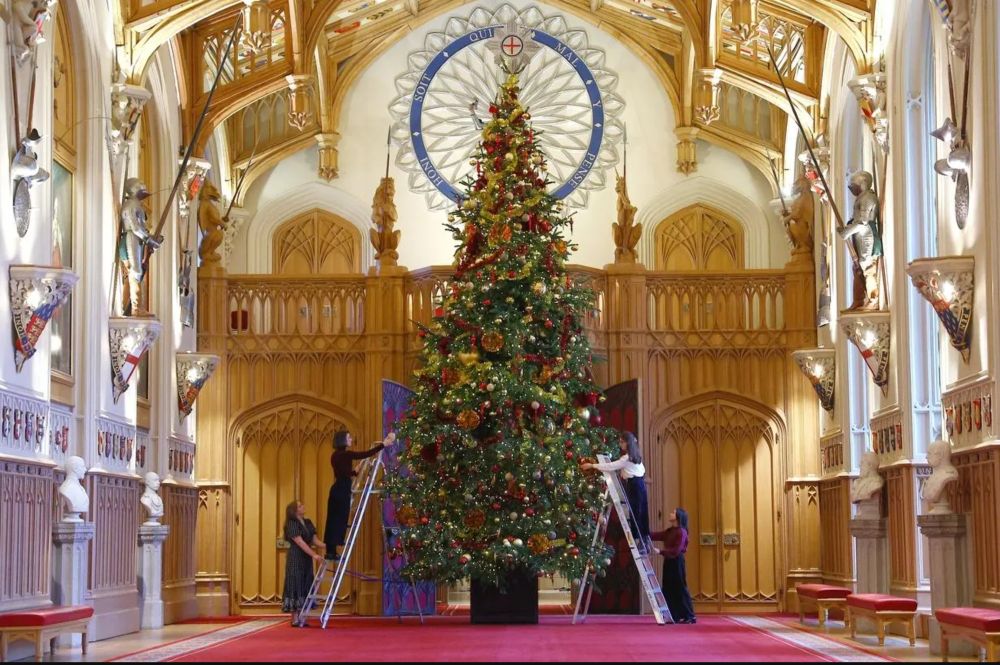 Royal household staff pose for a photograph next to decorated Christmas tree at Windsor Castle England. GETTY