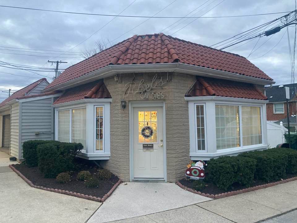 Established in 1917, the Rhebs Candies storefront is a small building: covered in tan formstone, has red clay roofing, with bay windows and a door in white trim.  This is where my family have purchased holiday chocolates for 4 generations.