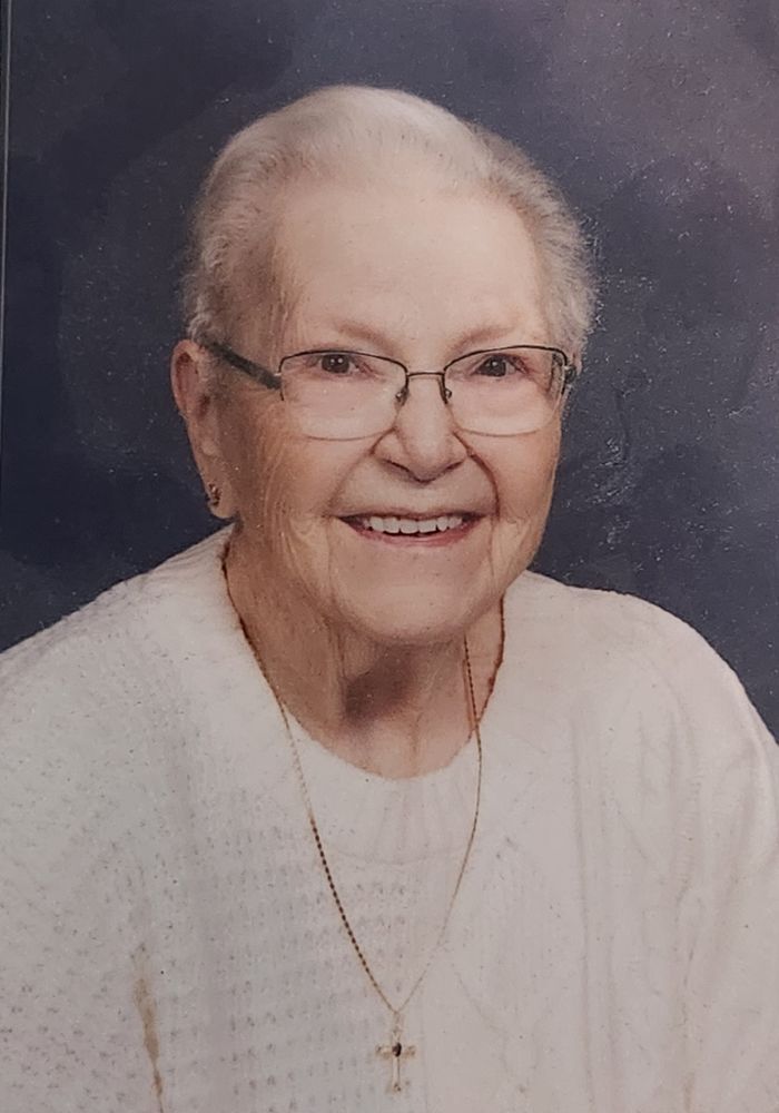 photo of Darlene Rodgers, an elderly woman with short white hair and glasses, wearing a white sweater and a gold cross necklace 