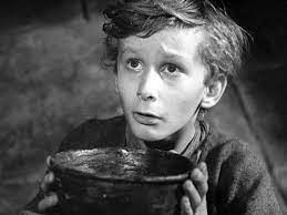 Photo of a child playing Oliver Twist.. with a bowl of gruel asking for more 