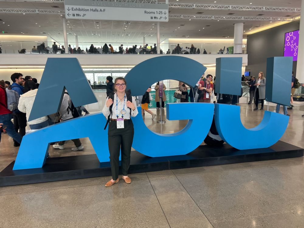 Armelle standing in front of a massive AGU logo in the conference hall 