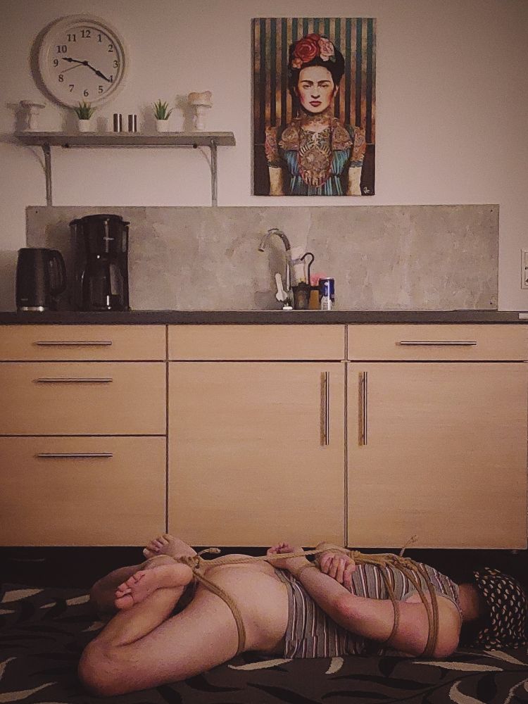 me laying down hog tied (feet and hands crossed behind the back and connected to each other) in front of a small kitchen, my face points away from cam

wearing a striped sleveless shirt and no undies

some trunks with a dots print is bit loose fit over my head like a mask

