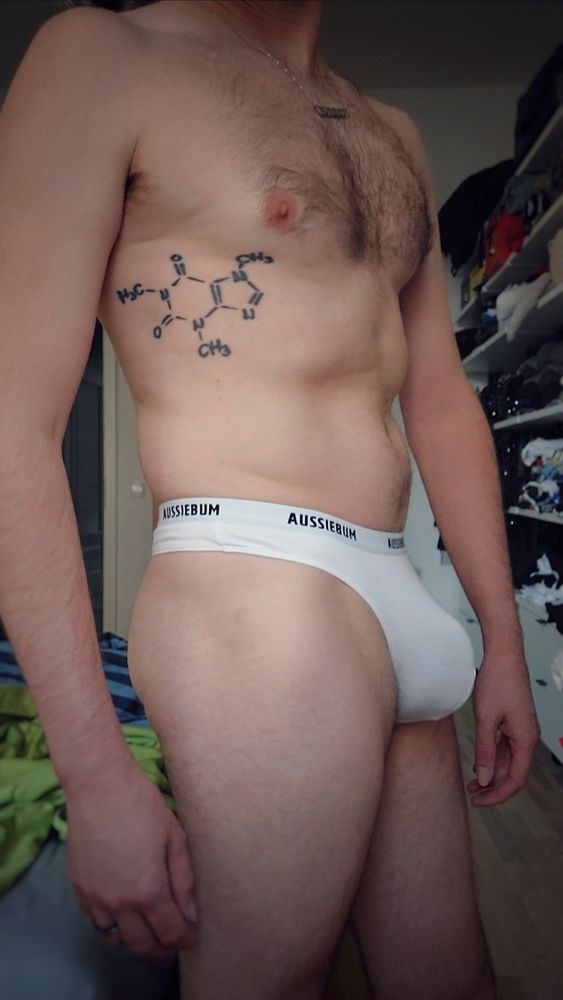 me posing sideways towards cam,  showing my right side

wearing a very tight fitting white aussiebum thong and showing of my bulge which pops out quit good

some für at my chest and a tattoo on my right upper body showing a chemical compound

In background slightly blurred bedroom 

