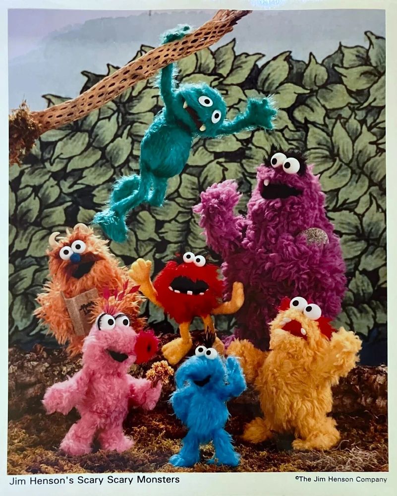A photo of seven monster puppets of different colors.