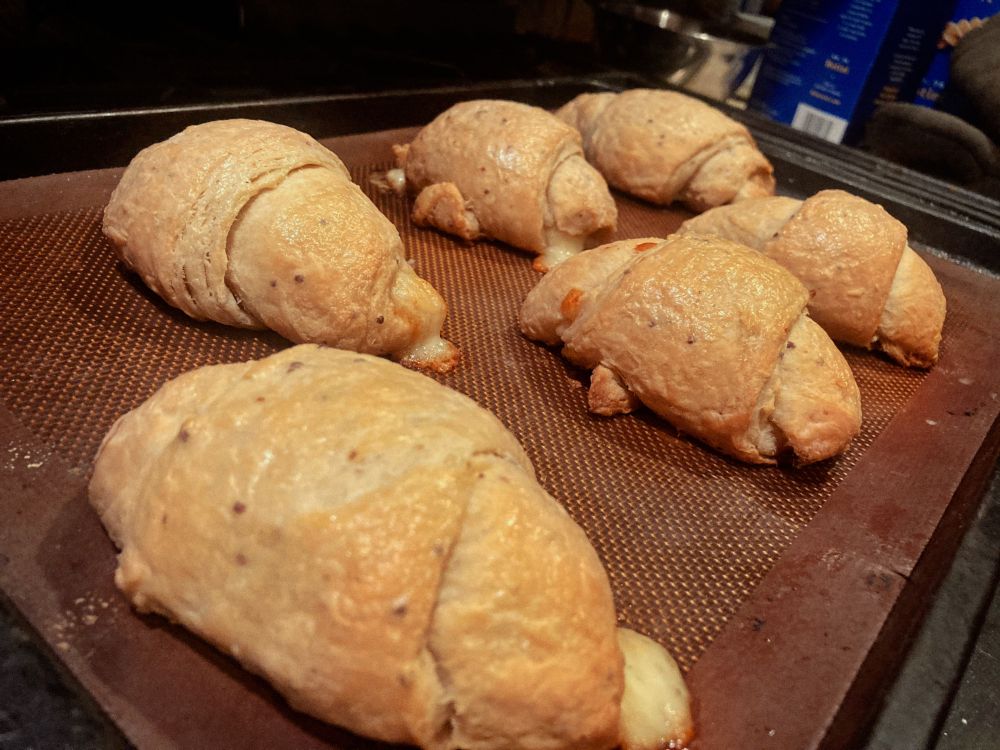Angled photo of 6 freshly baked croissants on a silpat