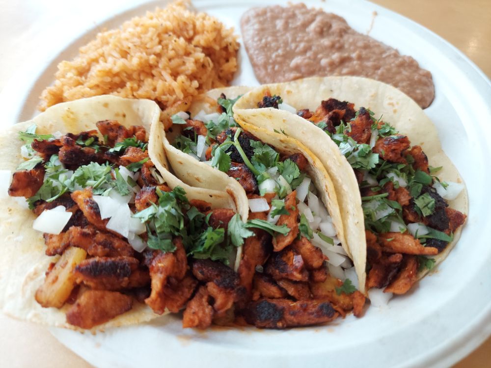 3 tacos with beans and rice on a paper plate. 