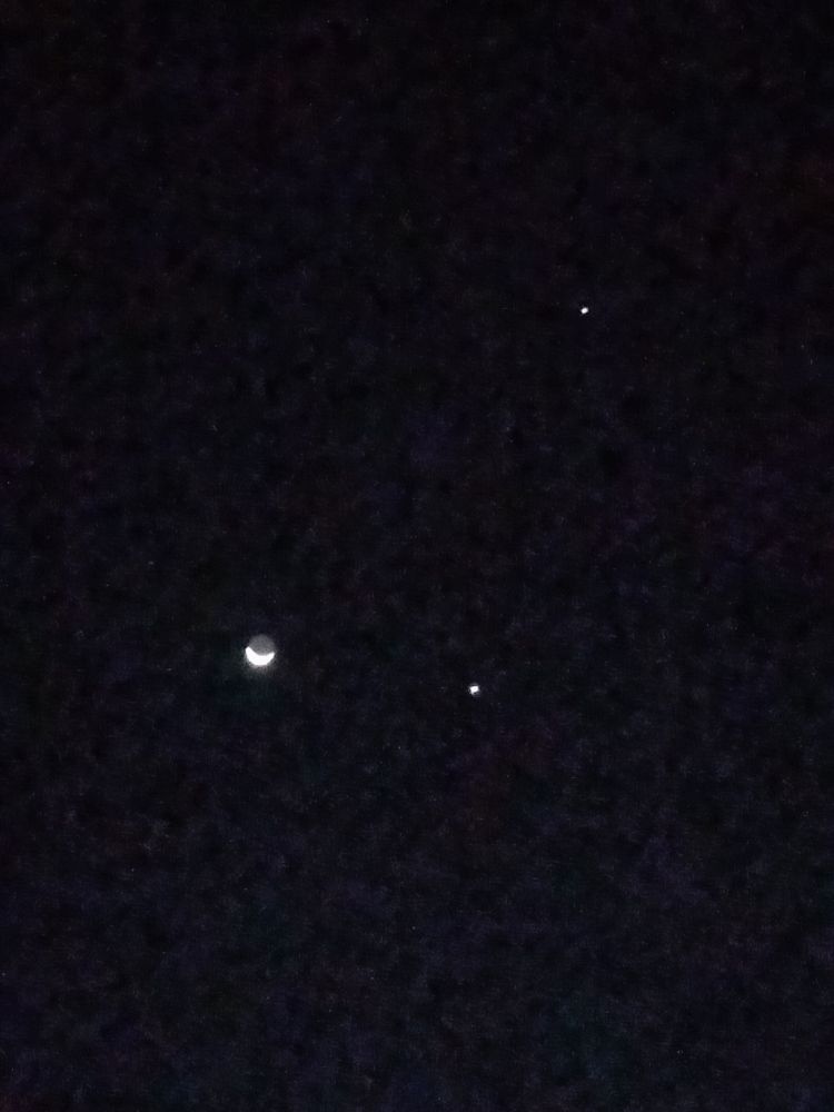 Black sky with the moon center left, Jupiter and Venus to the right of the moon