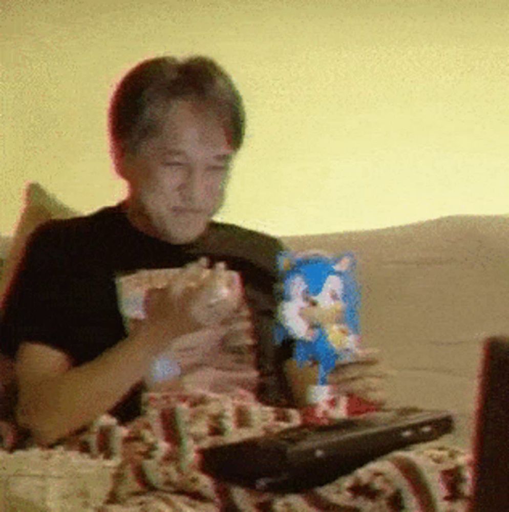 a man is sitting on a couch with a bag of sonic the hedgehog popcorn in front of him