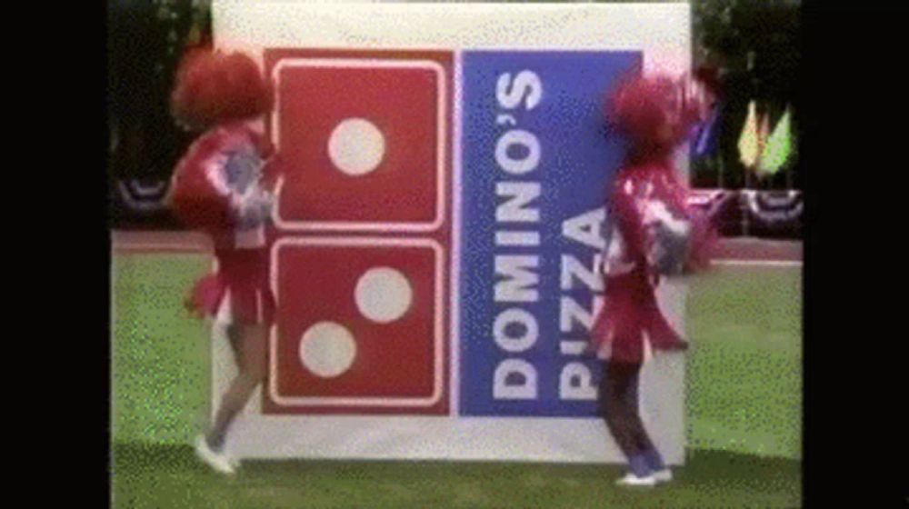 two cheerleaders are dancing in front of a domino 's pizza logo