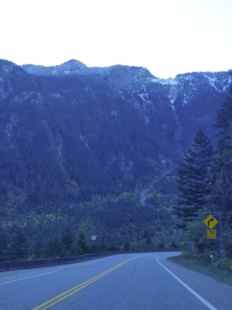 photo of the rocky mountains, towering over a street as if a wall stopping anything from continuing forward