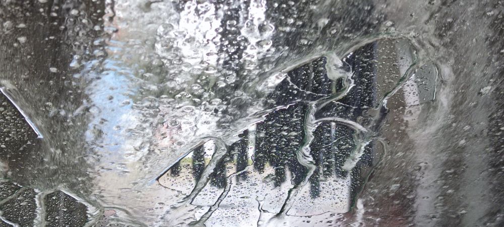 Von innen nach außen. 
Auto in einer Waschanlage. Wasserverwerfungen auf der Scheibe durch die Trocknung vom Fön, sorry fand kein anders Wort.
Dahinter Gummilamellen kurz vor der Ausfahrt der Waschanlage. 