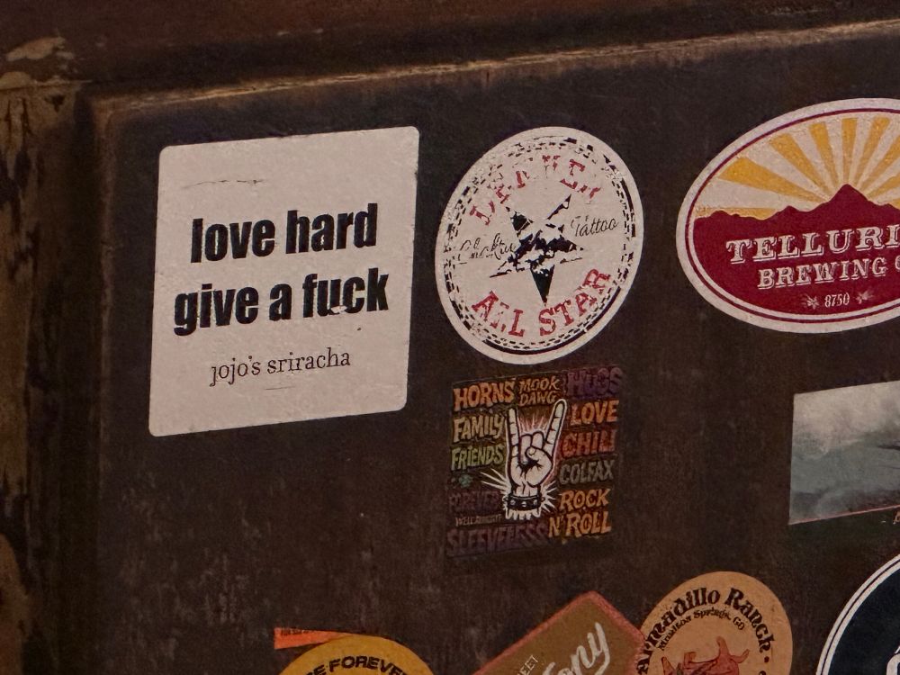 A series of bar room stickers, one being: Love hard give a fuck