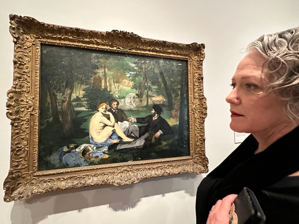 A woman standing in front of Manet’s color study for his painting ‘le dejeuner sure l’herbe.’