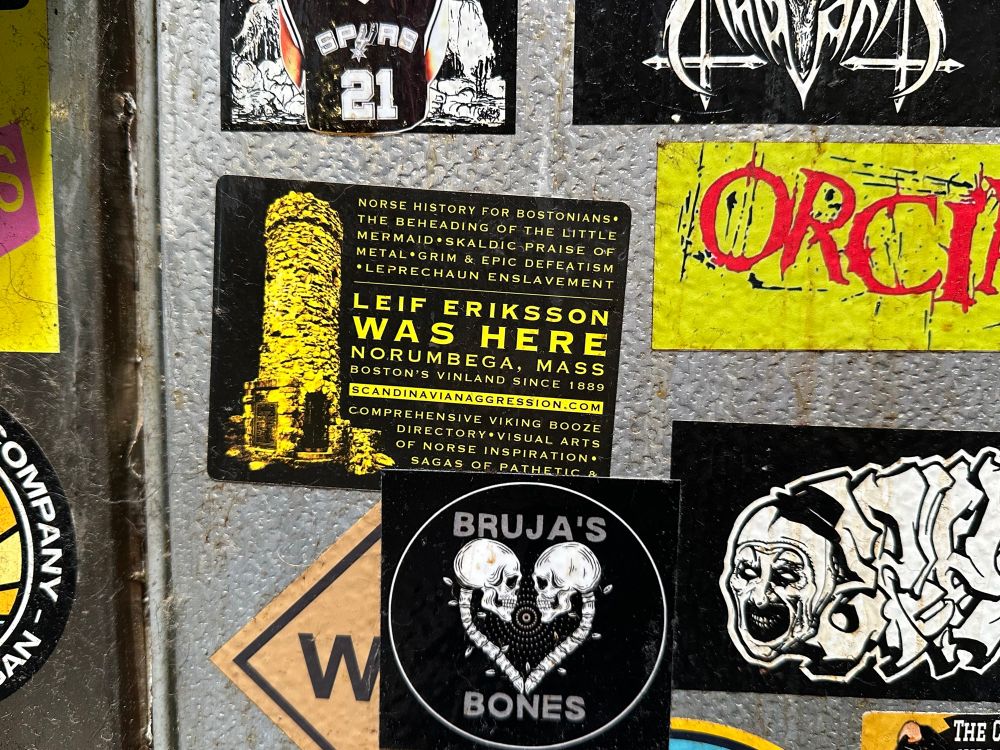 A ‘Lief Erikson was here’ sticker among many others on  bar room wall in Denver, CO.