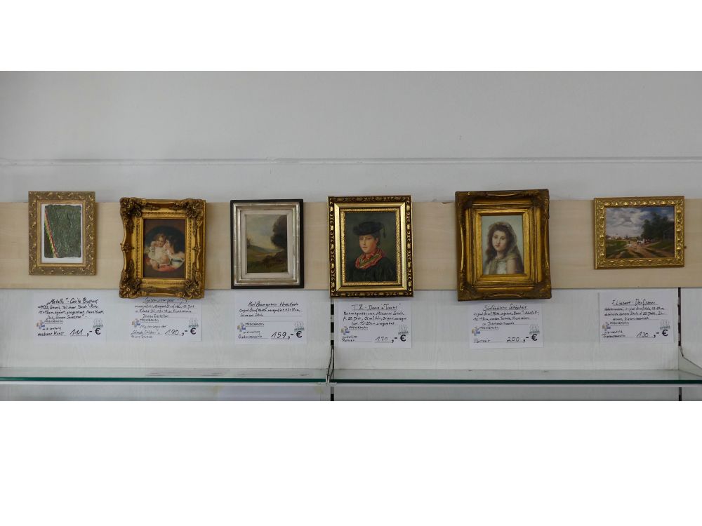 Es reihen sich Seite an Seite Zier- und Prunkgerahmte Kunstwerke. Diese sind mit Infoschildern ausgestattet, die etwas zu Künstlern und Stilistiken aussagen und die Bepreisung angeben. Landschafts- und Küstengemälde, Reisemalerei und Stillleben sowie historische Bewandnisse und Portraits sind die Motive der Gemälde.