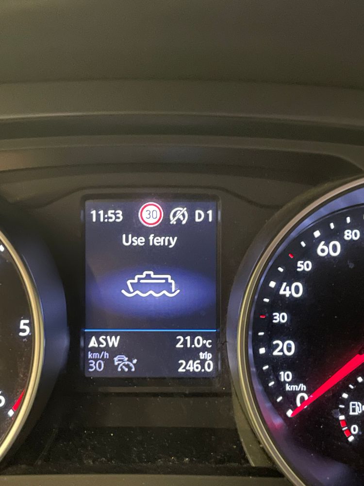 Close up of a car dashboard with a message saying ‘Use ferry’ and an icon of a large ship on water
