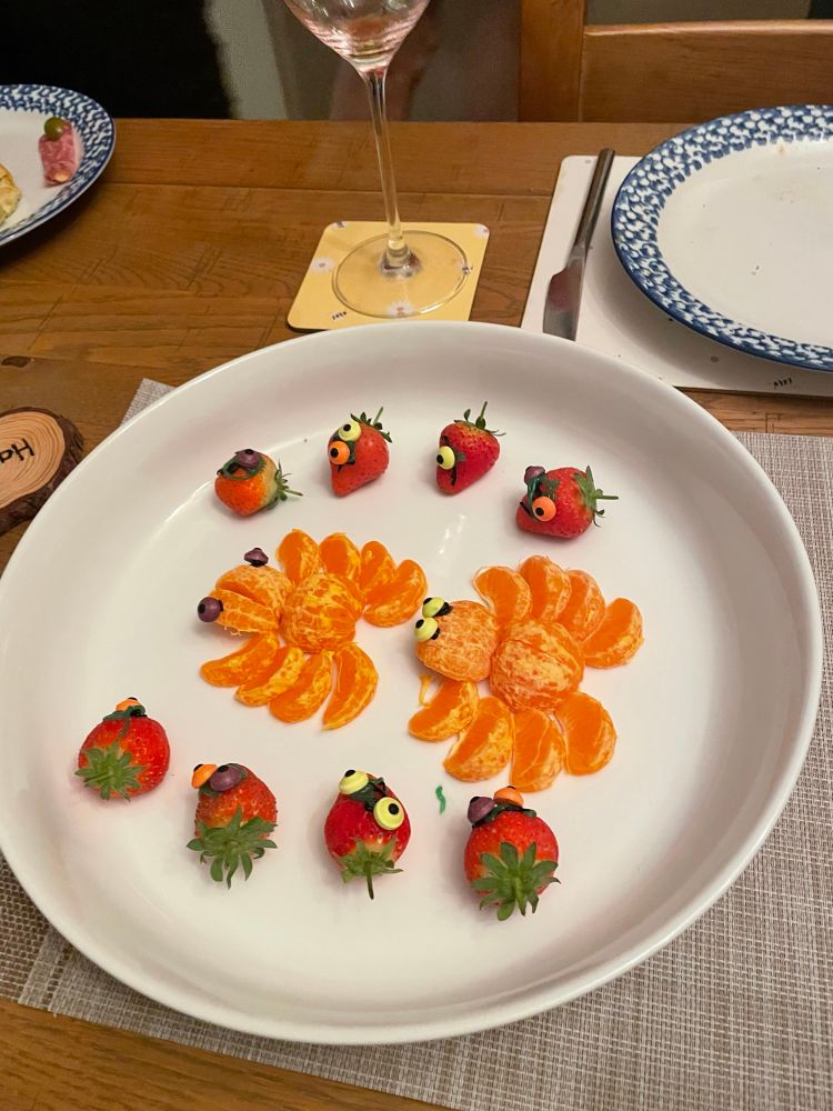Spiders made of orange segments and strawberries with googly eyes