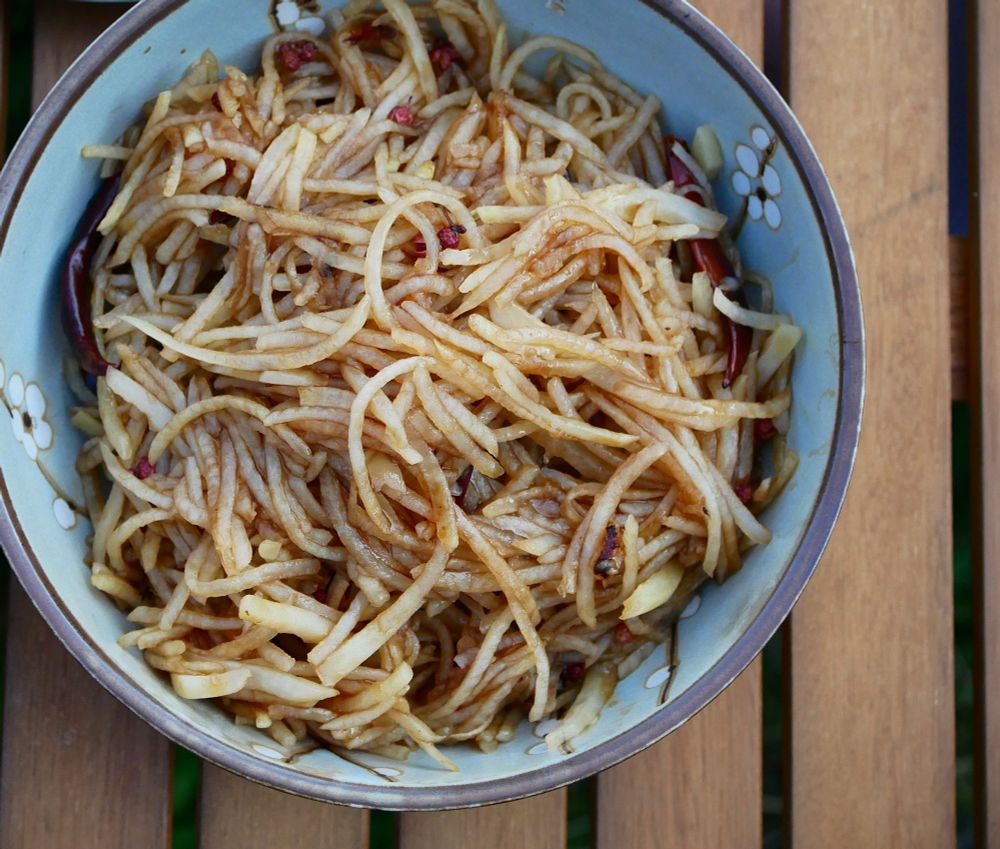 Top view close up of noodle like potatoes (stir fried) in a bowl