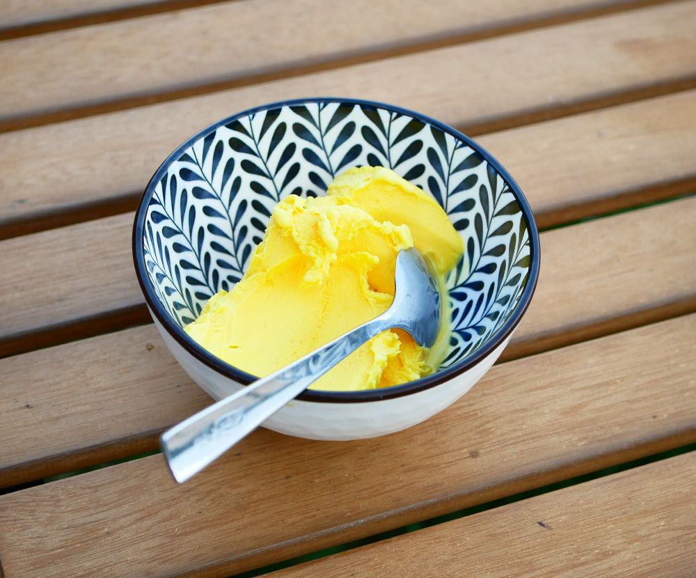 Bright yellow ice (gelato) in a bowl with spoon