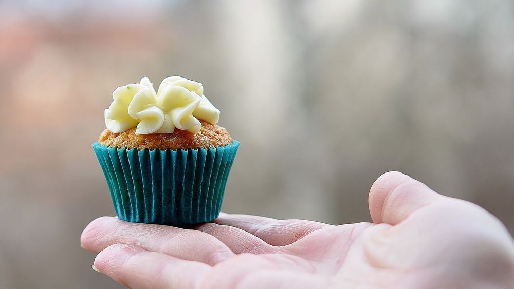 Outstretched hand with iced fairy cake, blurred background