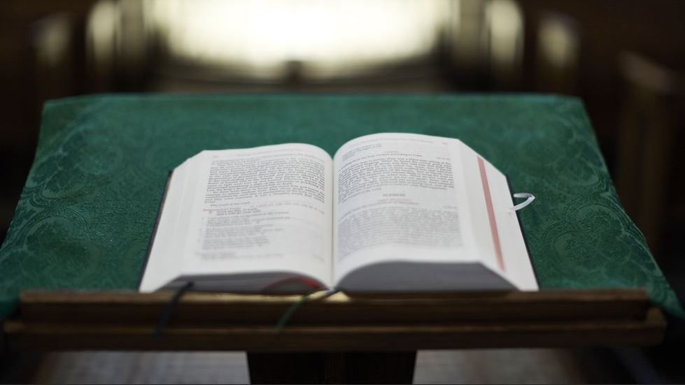 Open Bible on lectern, blurred background
