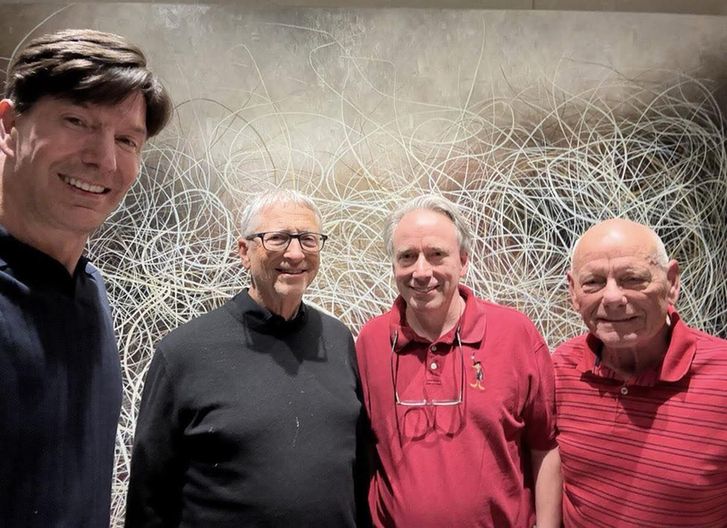 There are four people posing for a photo, with Bill Gates (black shirt) and Linus Torvalds (red shirt) in the center. We are not sure who the other two people are.