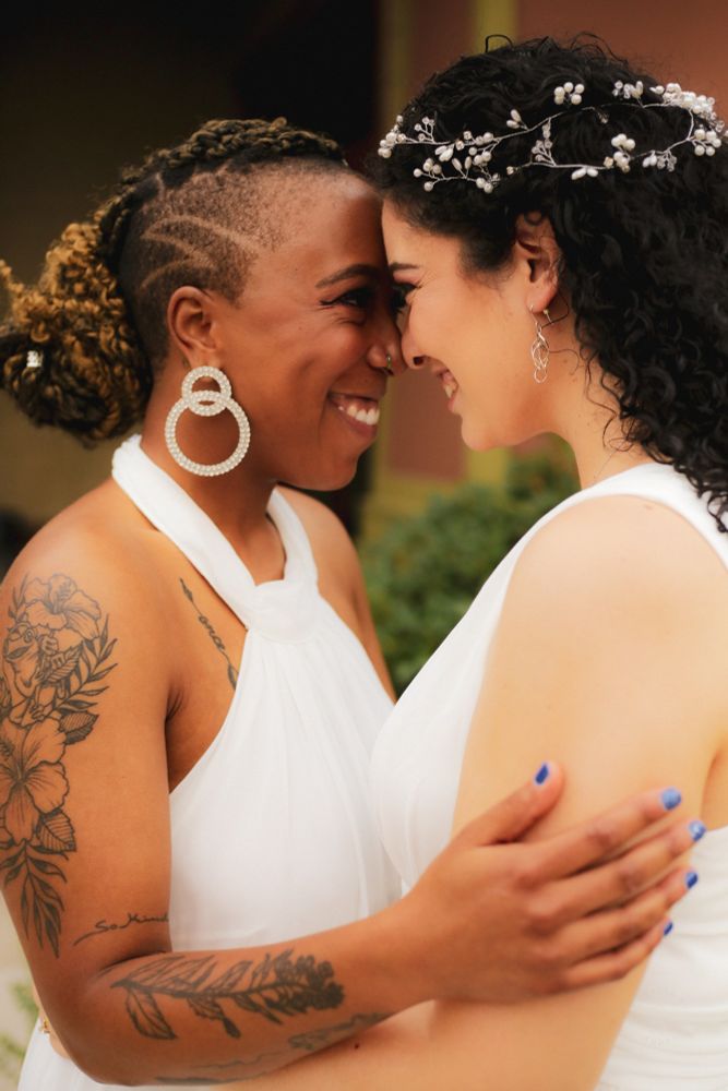 two brides in an embrace on their wedding day, forehead to forehead, both with huge smiles on their faces. (this is the OP and her wife.)