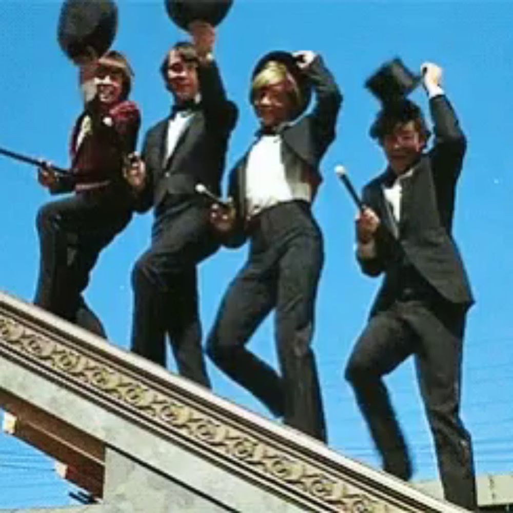 a group of men in suits and bow ties are standing on a ledge