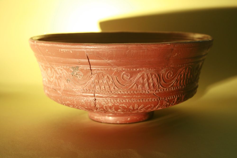 A restored Roman Samian bowl. Check it out. It's a beauty! Dramatic lighting shows off the scrolling patters to maximum effect. This Bad Boy is from our collections and dates to, give or take, 100AD (we can't be more precise as we don't have access to our catalogue at the moment). 