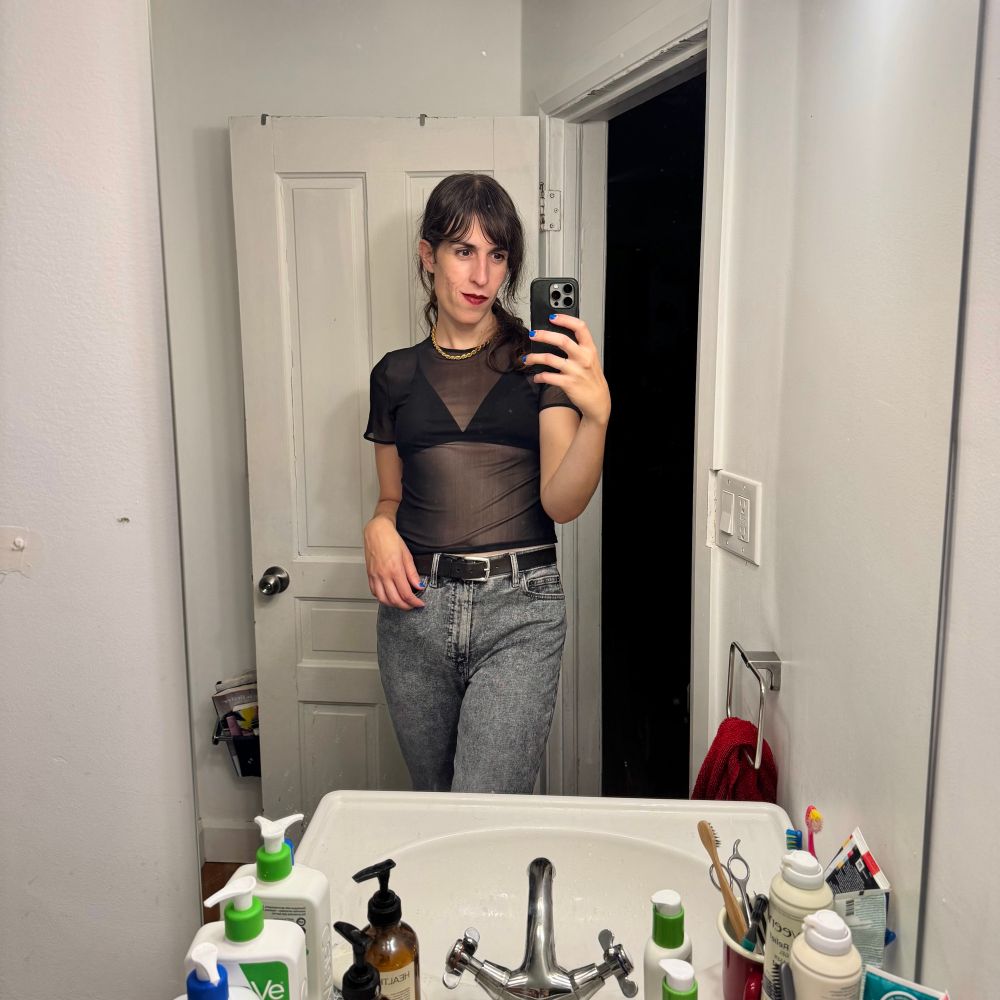 bathroom selfie; i’m wearing a mesh crop top over a bikini top and grey high waisted pants, and a darker colour of lipstick than i normally wear