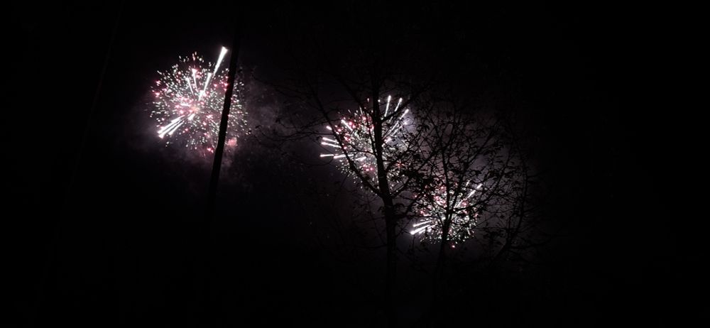 赤、緑、白っぽい黄色の色の花火が3つ上がってる写真