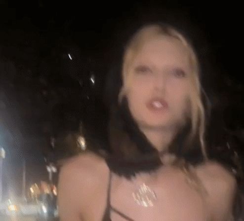 a blurry picture of a woman wearing a black dress and a gold necklace