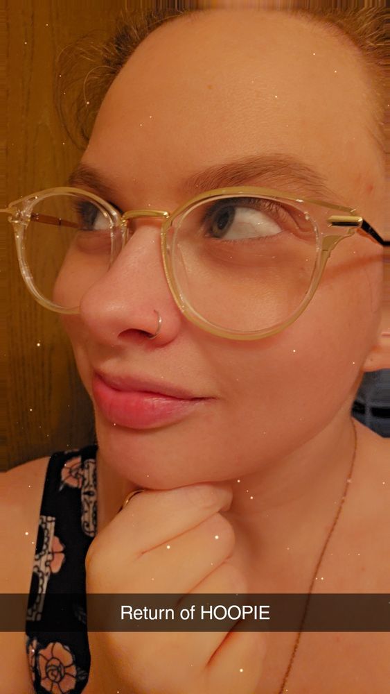 I look off to the side with my hand under my chin propping it up. My glasses are pushed up on the bridge of my nose and right under my glasses in my nostril is a silver nose hoop in my piercing. A caption on the photo says "Return of HOOPIE" 