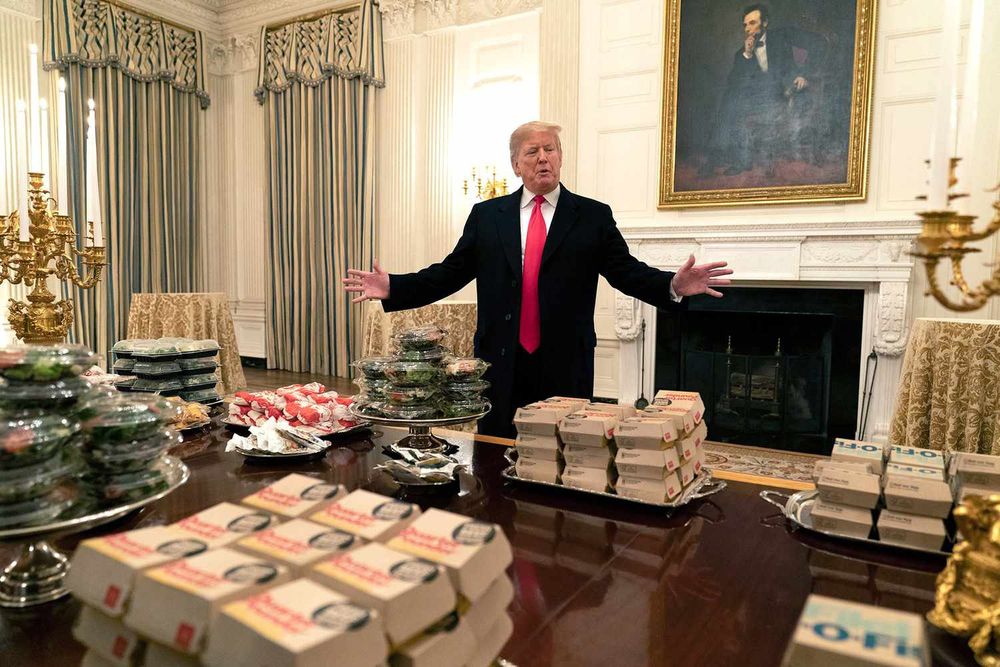 A photo of Trump, arms wide, presenting several dozen McSlop meals on the White House silver