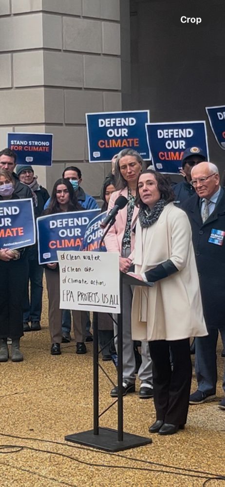 UCS President Gretchen Goldman speaks at a podium behind a hand-written sign that reads "Clean Water, Clean Air, Climate Action EPA Protects Us All"