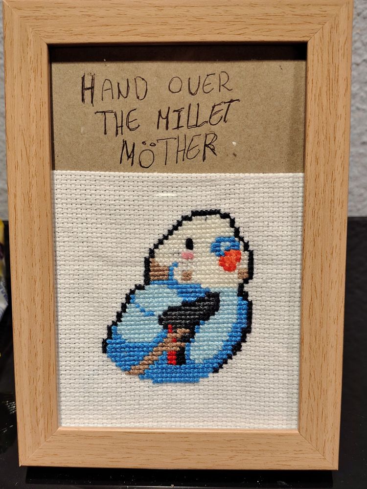 Cross stitch of a bird with a gun in a wooden frame 