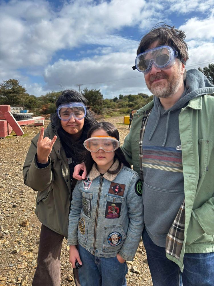 Three people with protective googles surrounded by mine waste and concrete structures