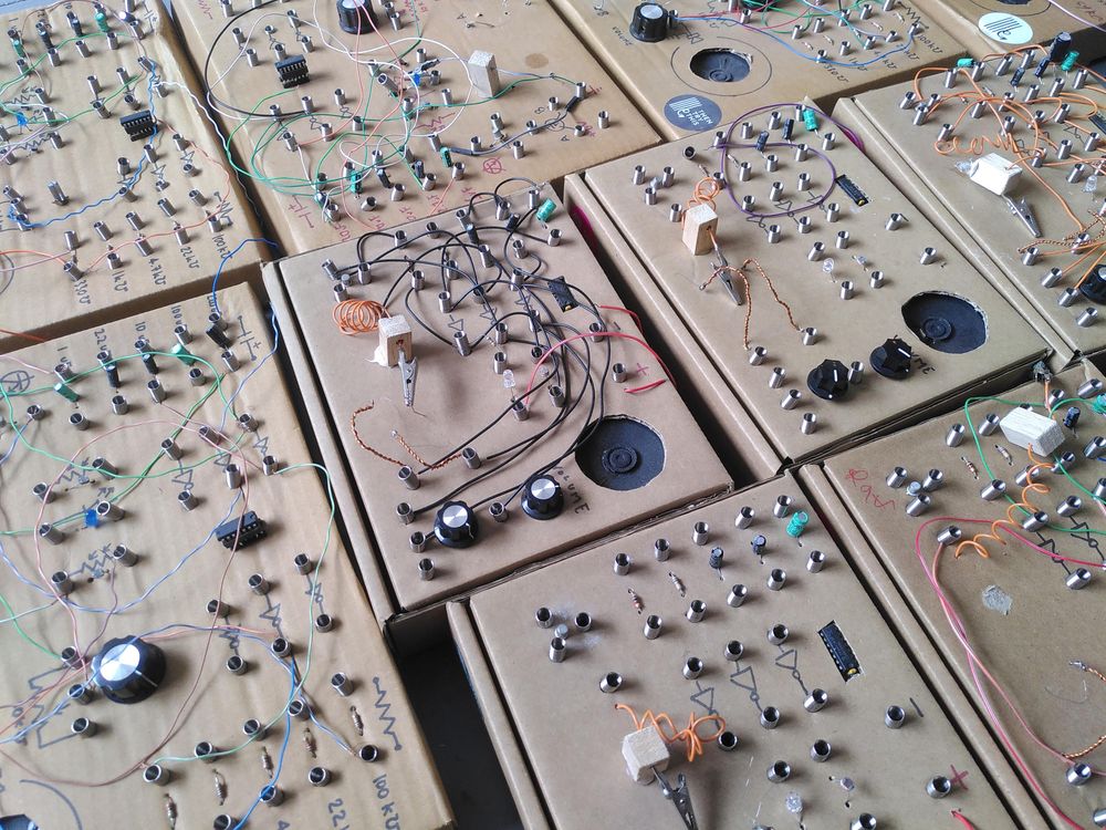 10 cardboard boxes all with electronic components, dials, speakers and crystal holders with spring and wires to connect them
